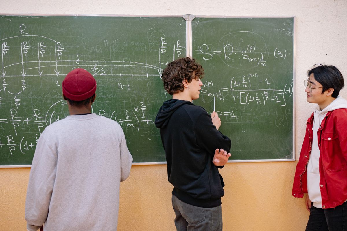 Students working through equations at a chalkboard